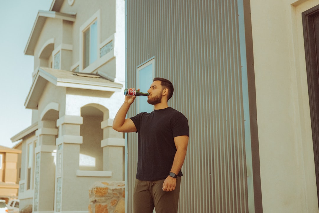 a man standing outside of a building drinking from a bottle