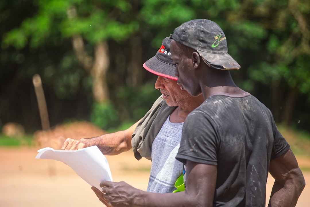 Two men looking at a document outdoors